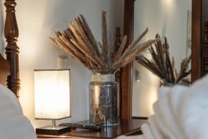 a vase filled with dry grass on a table next to a lamp at Petit Wannsee GmbH in Berlin +3 photos