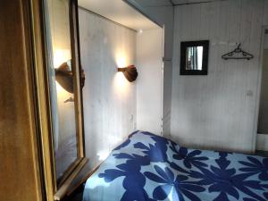 a bedroom with a bed with a blue and white blanket at CHALET A NATURISTE Le TIKI in Le Porge +13 photos