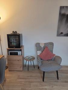 a living room with a chair and a television at Neues Ruhrtal Apartment 4 mit Balkon in Wickede (Ruhr)