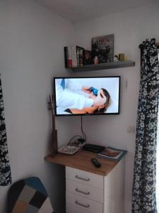 a television on a wall in a room with a desk at CHALET A NATURISTE Le TIKI in Le Porge