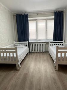 a bedroom with two beds and blue curtains at Затишна трьохкімнатна квартира у Львові in Lviv