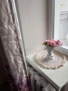 a vase with flowers on a table next to a window at Затишна трьохкімнатна квартира у Львові in Lviv +4 photos
