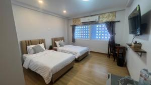 a hotel room with two beds and a television at บ้านตลาด สัตหีบ in Sattahip