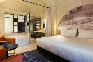 a bedroom with a bed and a tub and a bathroom at Le Grand Hôtel Dieu by SOWELL COLLECTION in Nîmes +68 photos