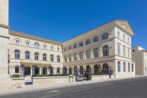 a large white building on a city street at Le Grand Hôtel Dieu by SOWELL COLLECTION in Nîmes