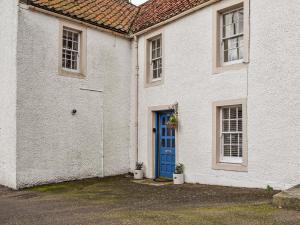 ein weißes Haus mit blauer Tür und blauen Fenstern in der Unterkunft Ardvar in Crail