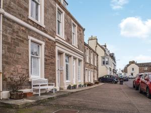 ein Gebäude mit einer Bank am Straßenrand in der Unterkunft Ardvar in Crail