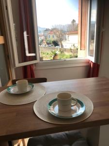 two cups and saucers on a wooden table with a window at Un petit nid au calme, à 4 minutes de la plage ! in Banyuls-sur-Mer