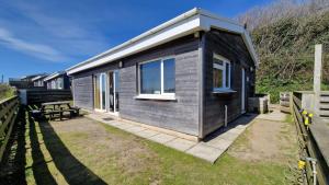 a small wooden cabin with windows on the grass at 6 The Dunes in Braunton