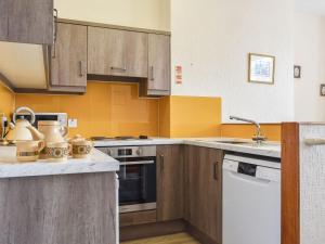 a large kitchen with wooden cabinets and appliances at Whitby Apartment in Commondale +3 photos