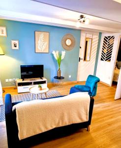 a living room with a couch and a blue wall at Le Beau Dolois - Appartement Climatisé au Coeur de DOLE avec Parking GRATUIT à proximité in Dole
