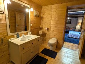 a bathroom with a sink and a toilet in a log cabin at Chambre Fleur bleue, les Volets Bleus in Laneuvelotte