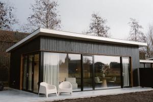 a small house with white chairs and windows at Polderlodge de Verademing in Goudriaan