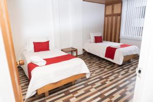 a bedroom with two beds with red and white sheets at HOTEL SUAREL CENTER in Duitama