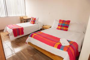 a bedroom with two beds and a table with a window at HOTEL SUAREL CENTER in Duitama