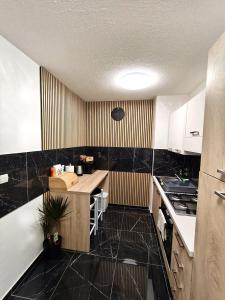 a kitchen with white cabinets and black tile floors at Apartment Aby - Free Parking & Self Check-in in Slavonski Brod