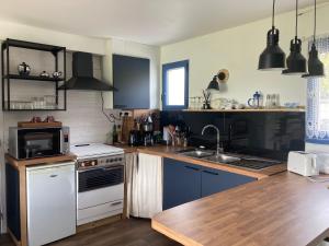 a kitchen with blue cabinets and a white stove top oven at Portec la mer et le sentier côtier à pied in Moëlan-sur-Mer +41 photos