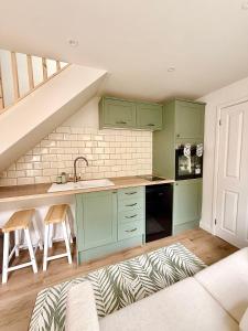 a kitchen with green cabinets and a staircase at Modern Cotswolds Studio in Bishops Cleeve