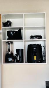 a white cabinet with a microwave and other appliances at Vila Lençóis Residence in Santo Amaro