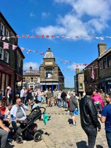 a crowd of people walking down a street with flags at Clock View - Haworth in Haworth