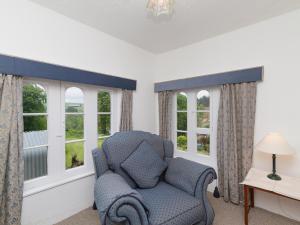 a living room with a chair and two windows at Symbister Suite in Turriff