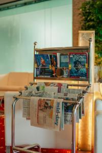 a magazine rack with newspapers and movies on it at Peninsula Grand in Mumbai