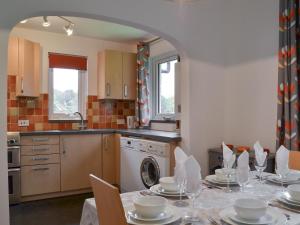 a kitchen with a table with plates and dishes on it at Sea Breezes in Totland