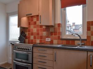 a kitchen with a stove and a sink and a window at Sea Breezes in Totland +17 photos