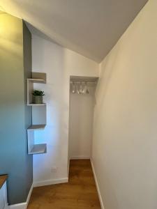 a hallway with white walls and a staircase with shelves at Grand studio 31 m2 plus mezzanine centre ville grasse in Grasse