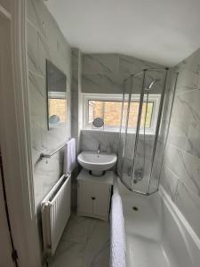 a white bathroom with a sink and a shower at Charming Contractors & Family Friendly 3-BR House in Harlow, Essex in Great Parndon