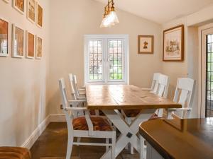 a dining room with a wooden table and white chairs at Flanders Cottage in Lymington