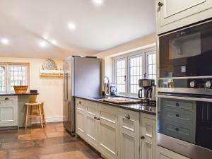 a kitchen with white cabinets and a black refrigerator at Flanders Cottage in Lymington