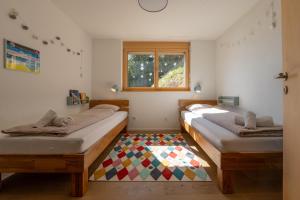 two beds in a room with a colorful rug at Gommer Sunna - Joderestutz in Reckingen - Gluringen