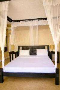 a bedroom with a large white bed with curtains at Lawford Apartment Malindi in Malindi +12 photos