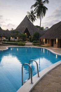 a swimming pool in front of some huts at Lawford Apartment Malindi in Malindi