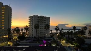 a city skyline with a building and palm trees at sunset at Villa Miel in Cala Millor