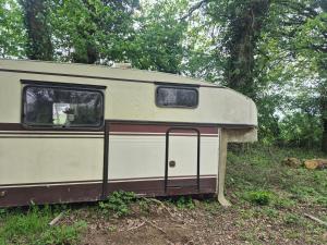 an old white trailer sitting in a field at L insolite in Maxent