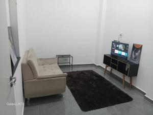 a living room with a chair and a television at Casa nova, completa, 3 quartos 1 com ar condicionado in Hortolândia