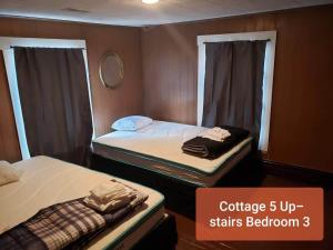 two twin beds in a small room with a mirror at Cottage 5 Duplex in Eckman ATV Fun and Rentals! in Northfork