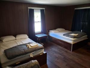 two beds in a room with a window at Cottage 5 Duplex in Eckman ATV Fun and Rentals! in Northfork