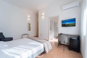 a bedroom with a bed and a desk and a tv at Albergo Ristorante Locanda Rosella in Giba