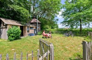 two people sitting in a yard next to a barn at Les insolites de la Ferme de Froidefontaine in Havelange