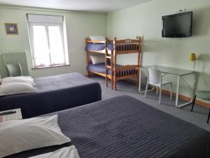 a room with two beds and a table and a television at Hôtel Relais des Vosges in Monthureux-sur-Saône