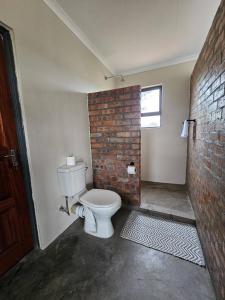 a bathroom with a toilet and a brick wall at Troupant - Luxury Bush Unit in Askham