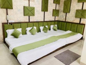 a large bed with green and white sheets and pillows at Hotel SR Siddhivinayak Mathura in Mathura