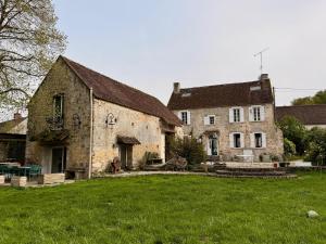an old stone building with a green field in front of it at Former riverside rectory in Nanteau-sur-Lunain