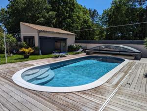 a swimming pool on a wooden deck next to a house at La perle in Les Mathes
