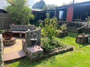 a garden with a stone bench and a table at Bohemian Garden Cottages in Kaapsehoop