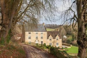 a large stone house in the middle of a field at Week Farm Manor in Wellow