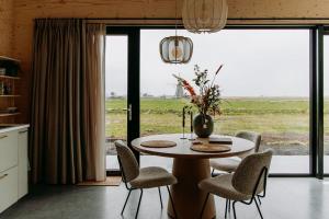 a table and chairs in a kitchen with a large window at Polderlodge de Ontmoeting in Goudriaan +33 photos